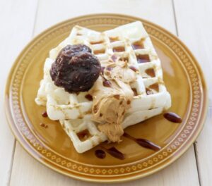 Mochi waffles made in a waffle maker, topped with red bean paste and syrup